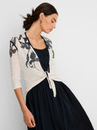 Cream open cardigan with dark navy floral print and trim, tied at the waist. It has 3/4 sleeves.