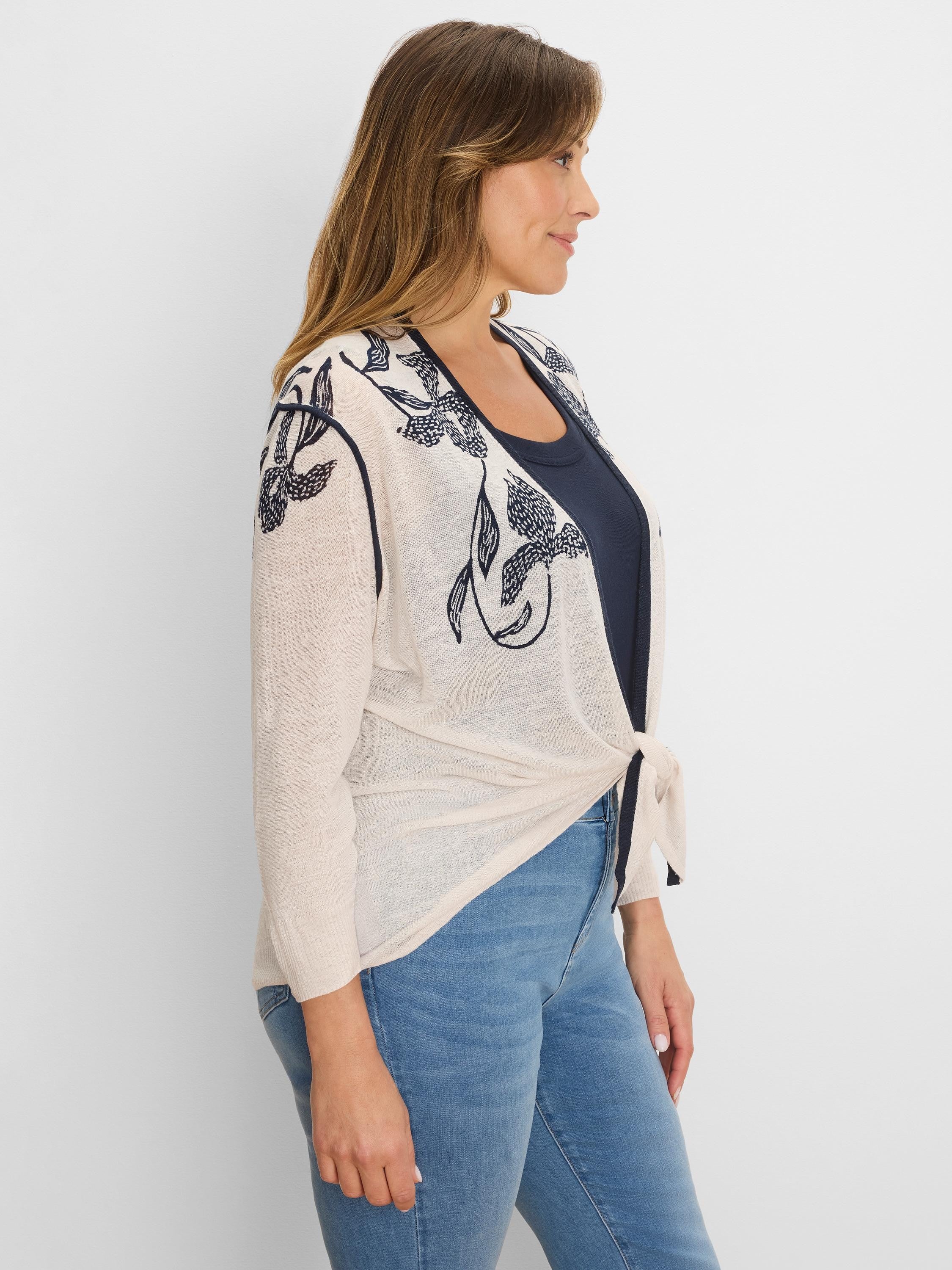 Light beige open cardigan with navy floral print, tied at the waist.