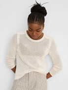 Off-white open knit mesh sweater with a crew neck, long sleeves, and ribbed trim.