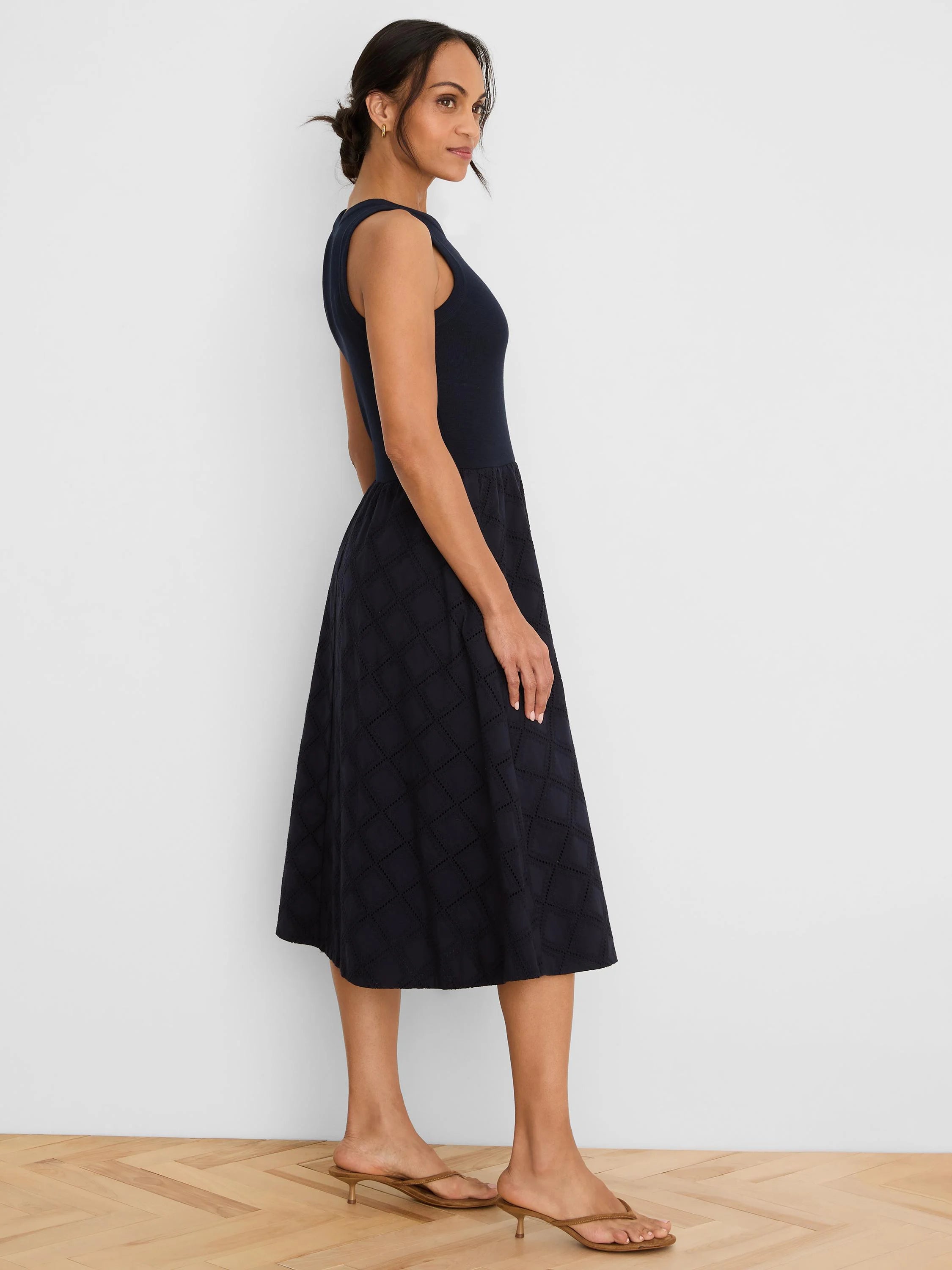Navy blue sleeveless dress with a fitted top and a flared midi skirt featuring a diamond eyelet pattern.