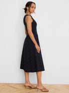 Navy blue sleeveless dress with a fitted top and a flared midi skirt featuring a diamond eyelet pattern.