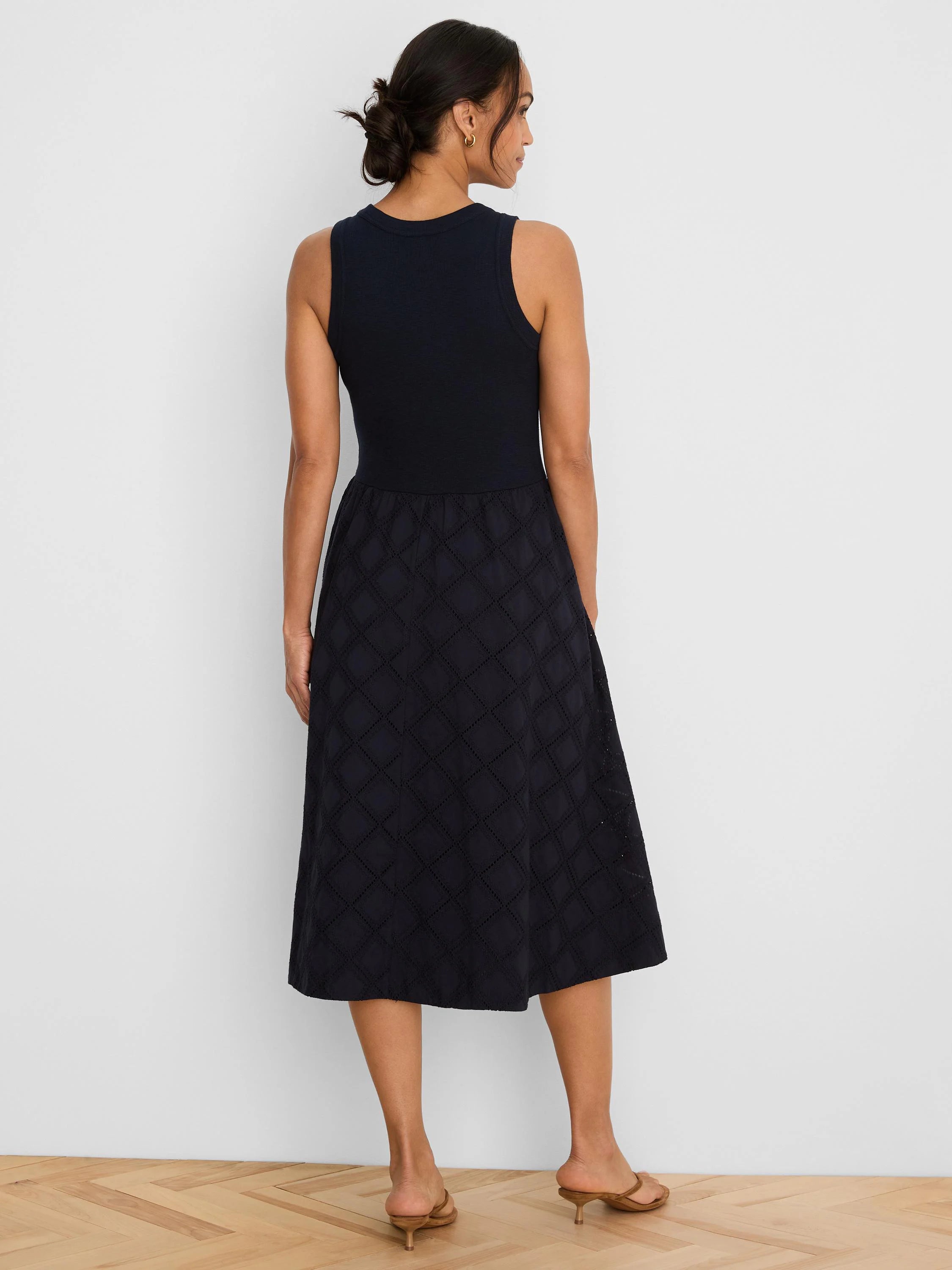 Navy sleeveless midi dress with ribbed top and diamond eyelet skirt, worn by a model from behind.