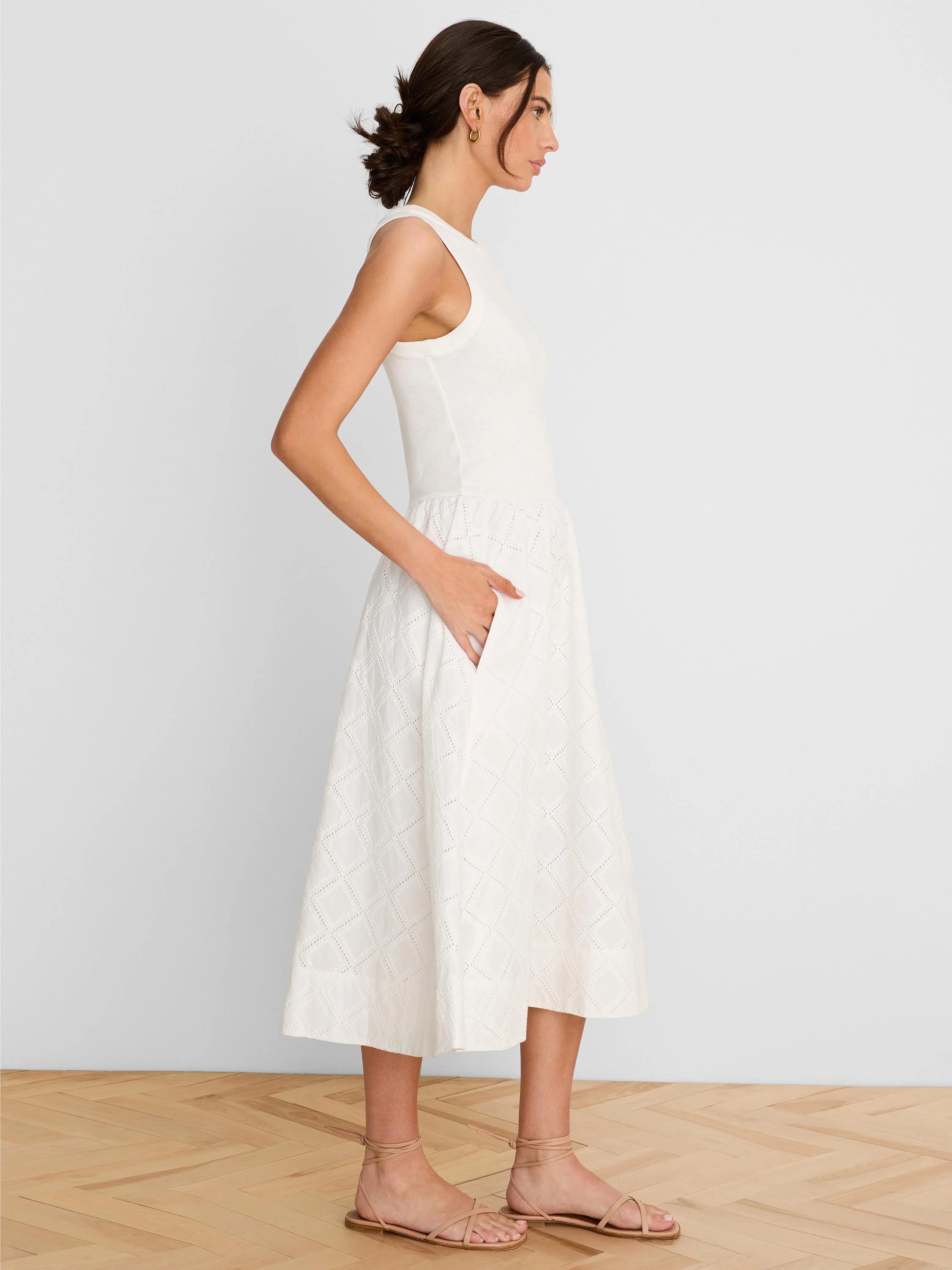 White sleeveless dress with a ribbed top and a diamond eyelet patterned midi skirt featuring side pockets.