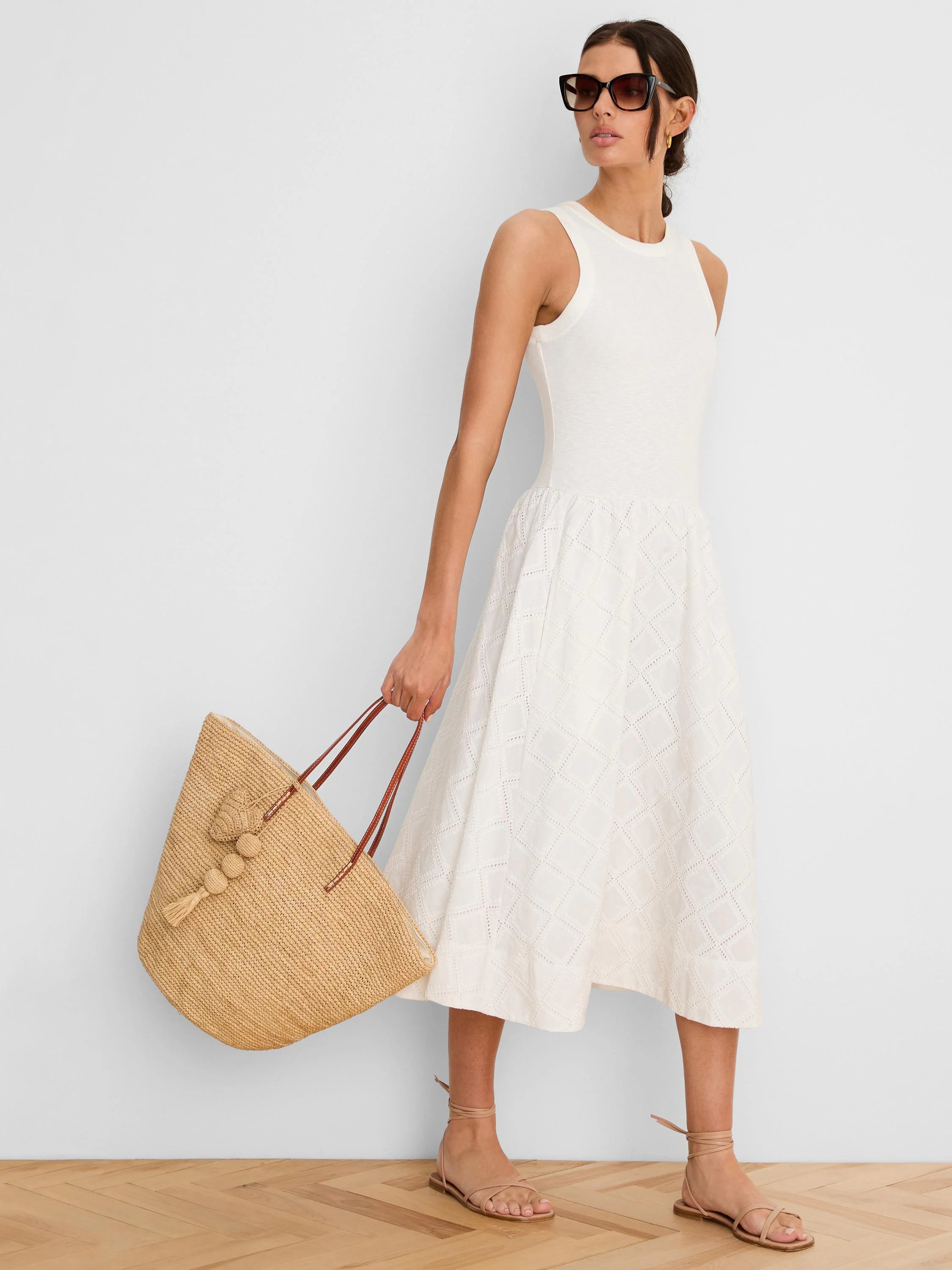 Cream sleeveless midi dress with a fitted bodice and flared skirt featuring a diamond eyelet pattern.