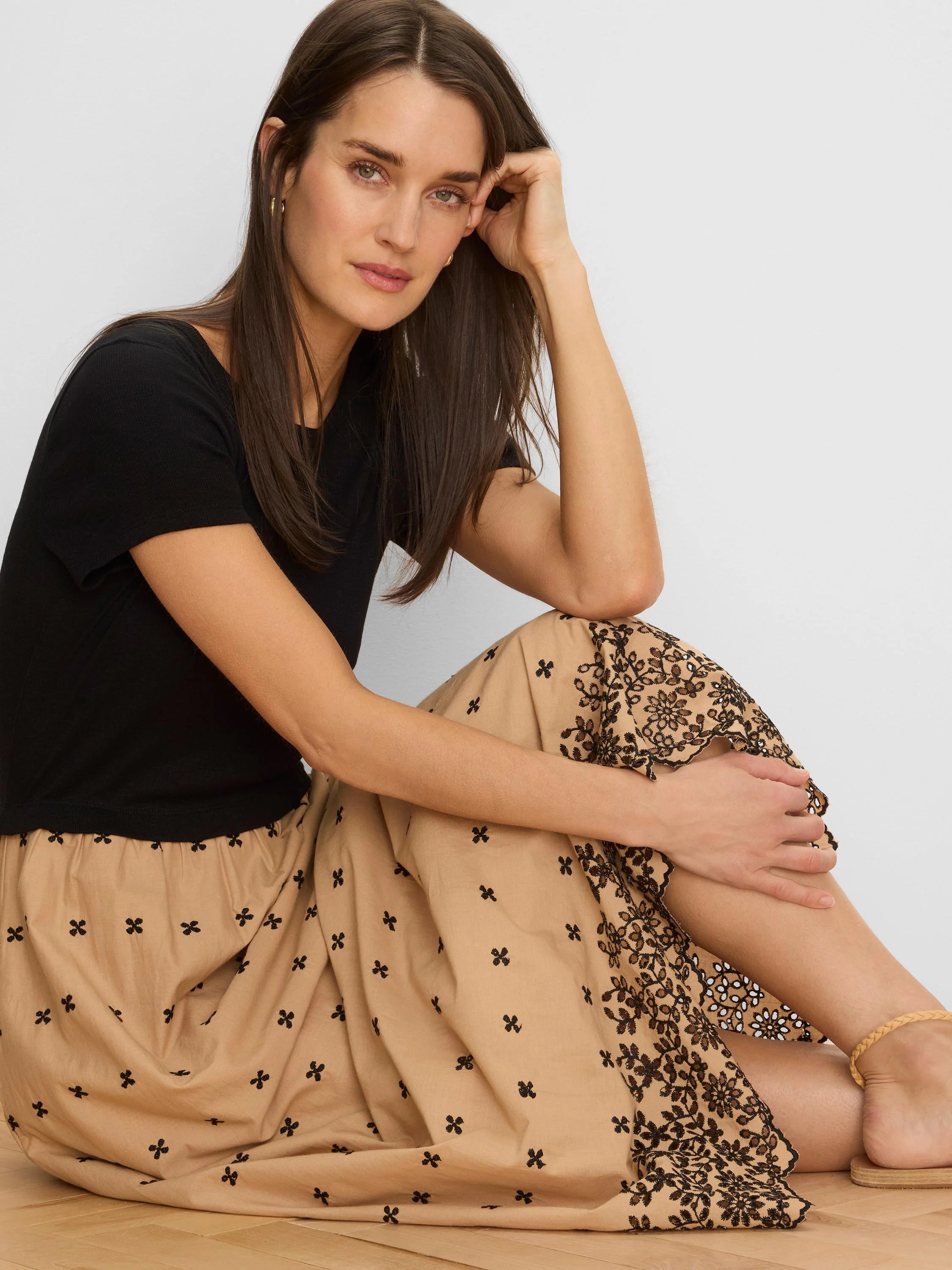 Tan dress with black embroidery: small scattered cross motifs and intricate floral cutwork patterns.