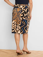 Knit knee-length skirt with black, tan, cream, blue stylized floral-geometric pattern.