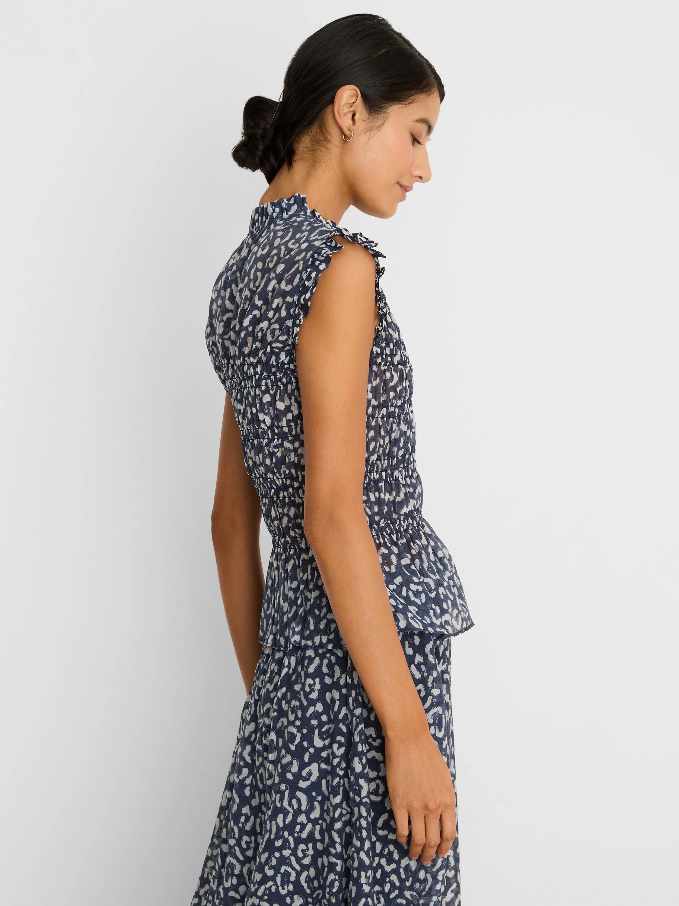 Navy blue top with light leopard sketch print, smocked waist, ruffled neck, sleeveless, and peplum hem.
