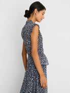Navy blue top with light leopard sketch print, smocked waist, ruffled neck, sleeveless, and peplum hem.