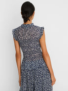 Indigo top with white abstract leopard print, smocked waist, ruffled mock neck, and cap sleeves.