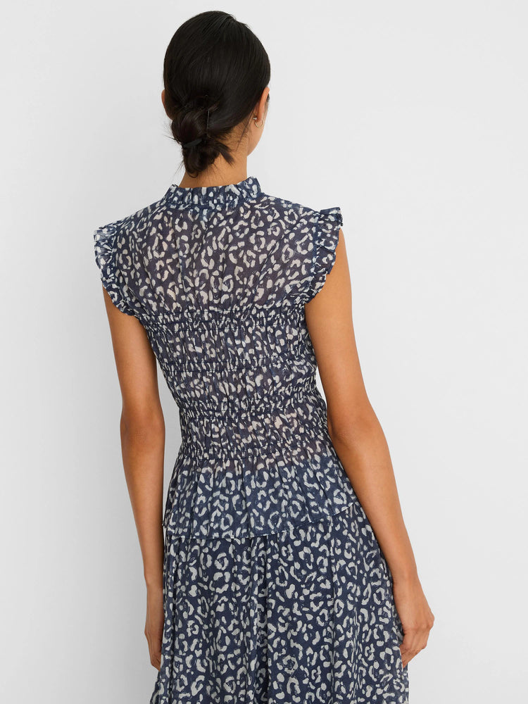Indigo top with white abstract leopard print, smocked waist, ruffled mock neck, and cap sleeves.