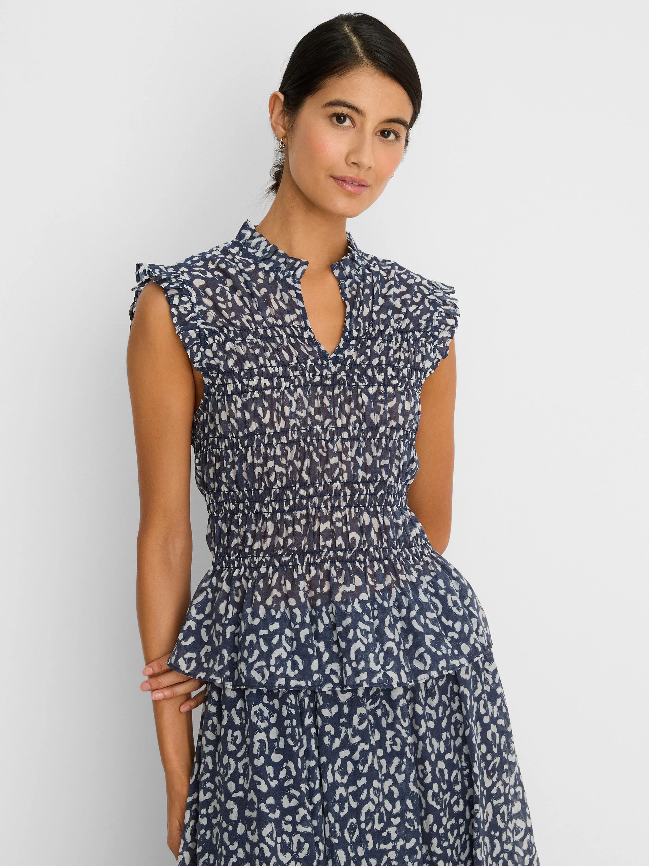 Navy and off-white leopard sketch smocked top with ruffled cap sleeves, stand collar with V-neck, and tiered hem.