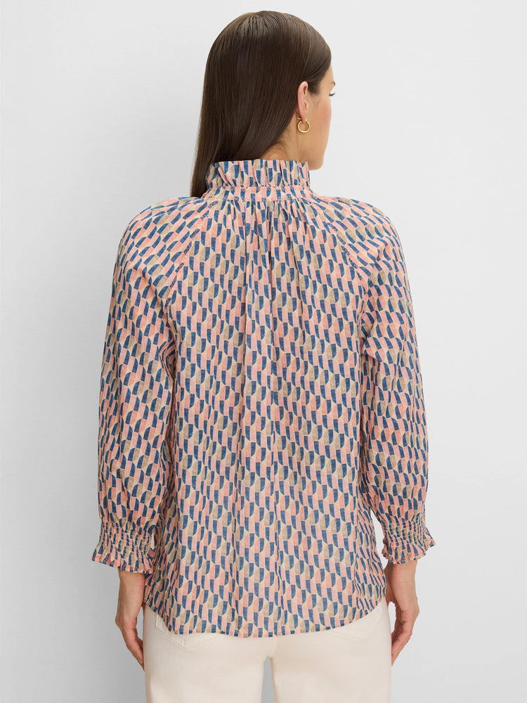 Back of woman in a pink, blue & tan geometric cotton crinkle shirt with ruffled neck and smocked cuffs.