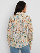 Cream cotton lawn, long-sleeved, collared shirt with blue, orange, and green watercolor floral print.