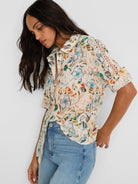 Off-white cotton lawn shirt with multicolor pressed flower print. Collared, with rolled sleeves showing lace cutwork.