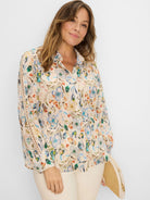 Cream shirt with watercolor floral print in muted blue, teal, orange, green. Features ladder lace detail on sleeves.