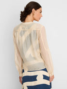 Pale cream sheer long-sleeve shirt with gathered back yoke and buttoned cuffs.