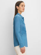 Medium blue cotton lawn shirt with dimensional floral appliqués on the front, shown on a model.