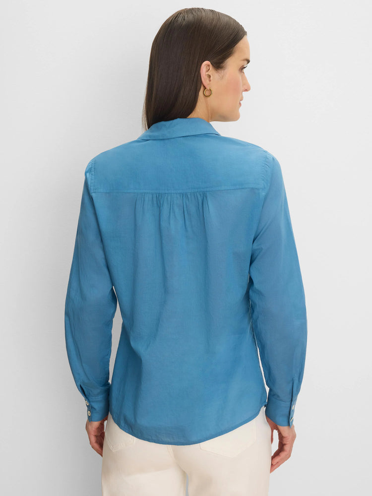 Blue long-sleeved cotton lawn shirt, back view. Features a collar, gathered back yoke, and curved hem.
