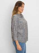Loose top with blue, brown, and black speckled print, ruffle neck, and button placket.