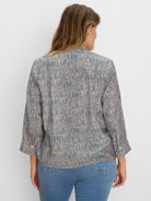 Loose speckled top in muted blue, black, & peach on light fabric with 3/4 length rolled-up sleeves.