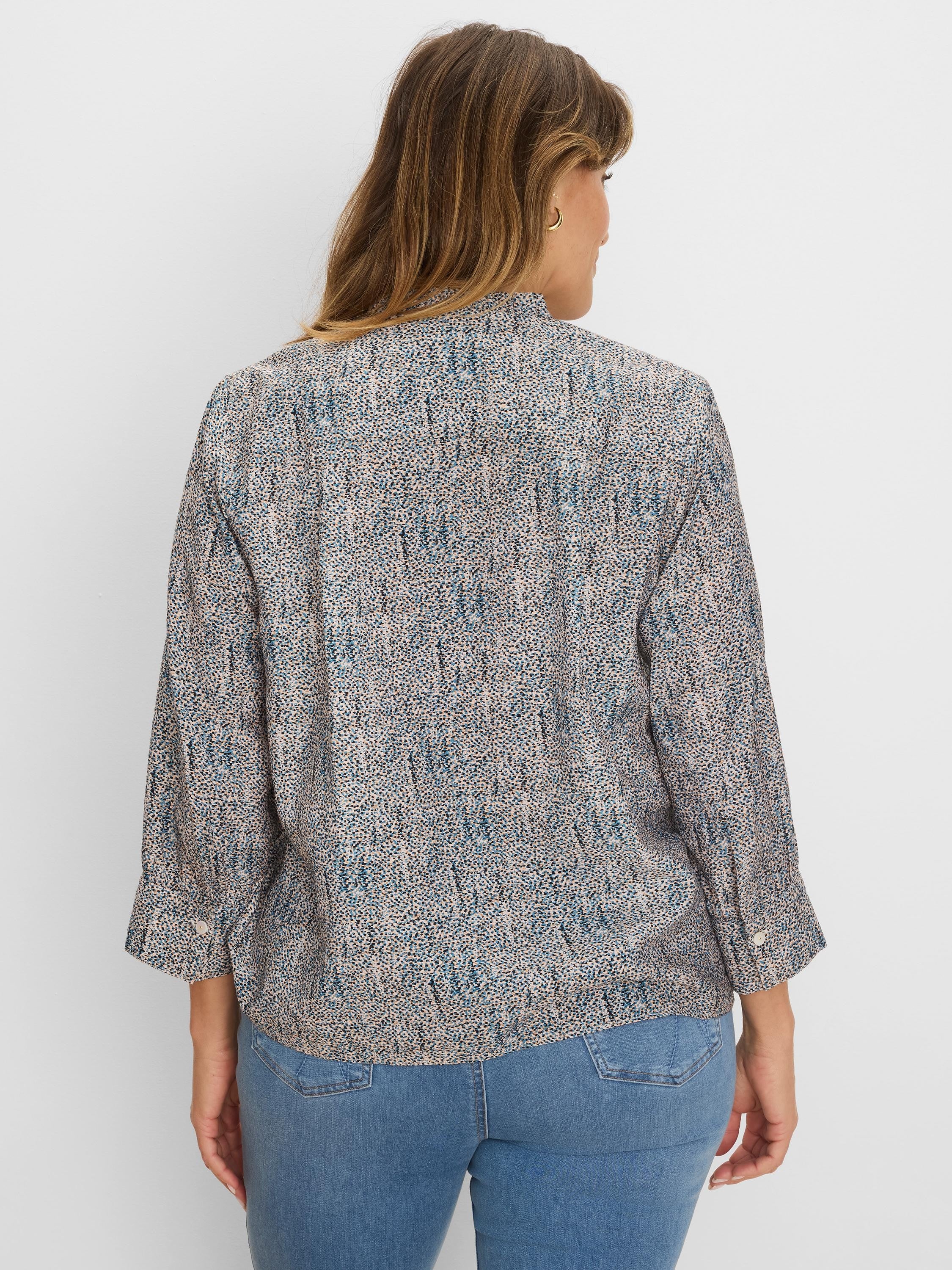 Loose speckled top in muted blue, black, & peach on light fabric with 3/4 length rolled-up sleeves.