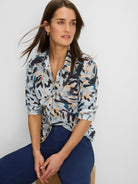 Light blue button-down shirt with abstract navy, teal, and tan brushstroke pattern. Sleeves are rolled up.