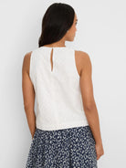 White sleeveless top with diamond eyelet pattern. Keyhole opening with button at back neck.