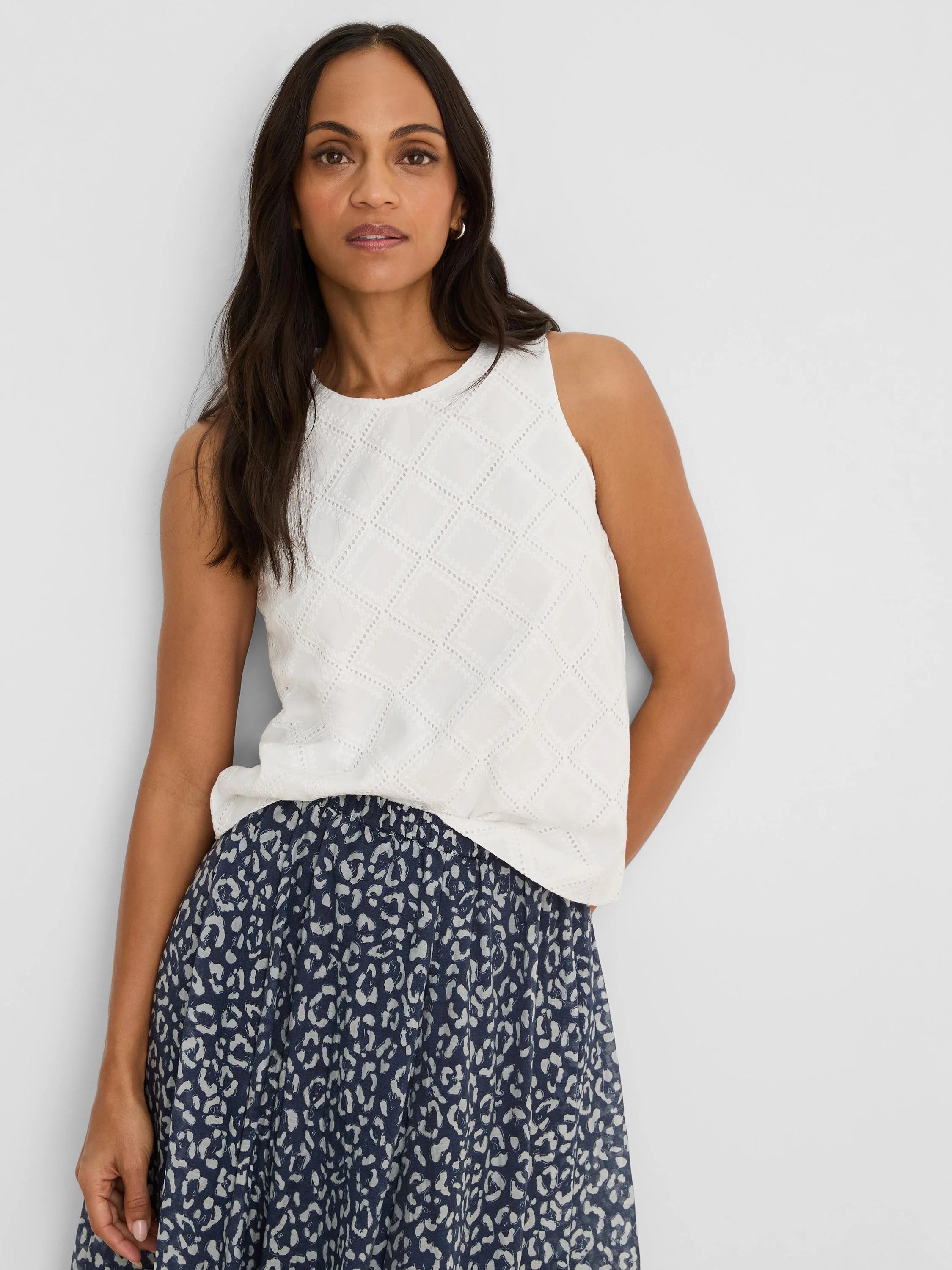 Off-white sleeveless top with a round neck and an all-over diamond eyelet pattern.
