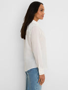 White long-sleeved cotton shirt with subtle ruffles along the button front.