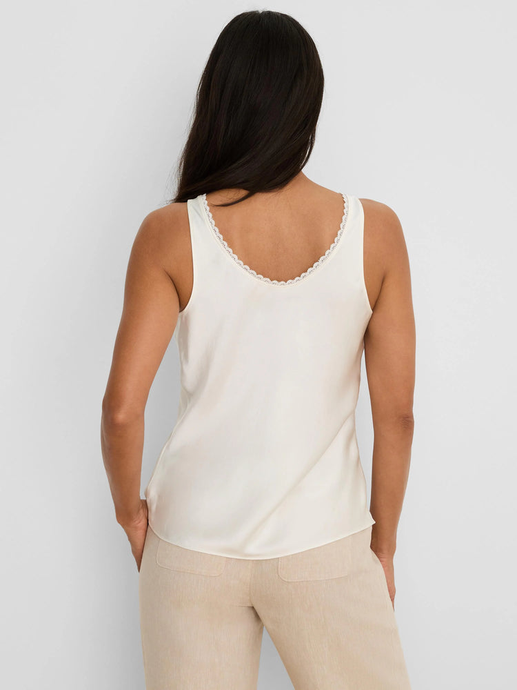 Off-white glossy tank top with white lace trim around the back scoop neckline, modeled from behind.