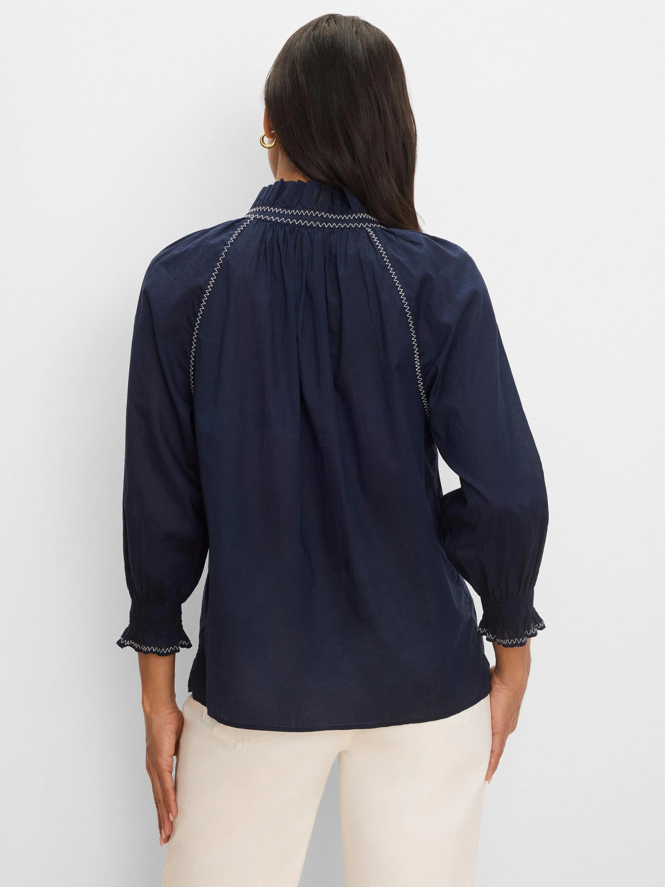 Navy blue crinkle shirt, back view. Features white zig-zag stitching on ruffled neckline, shoulder lines, and smocked cuffs.