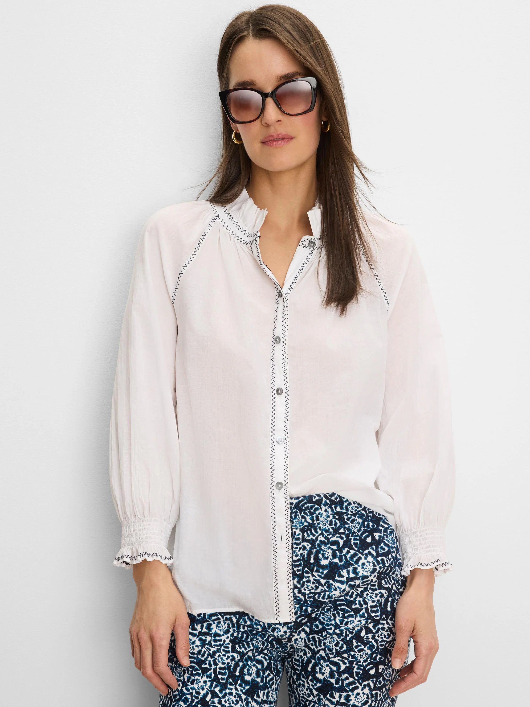 White crinkle shirt with dark zig-zag stitching on the ruffled collar, button placket, and smocked cuffs.