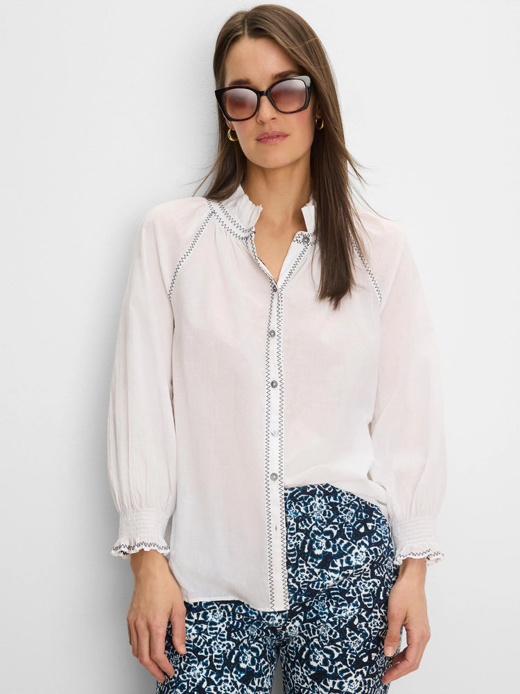 White crinkle shirt with dark zig-zag stitching on the ruffled collar, button placket, and smocked cuffs.