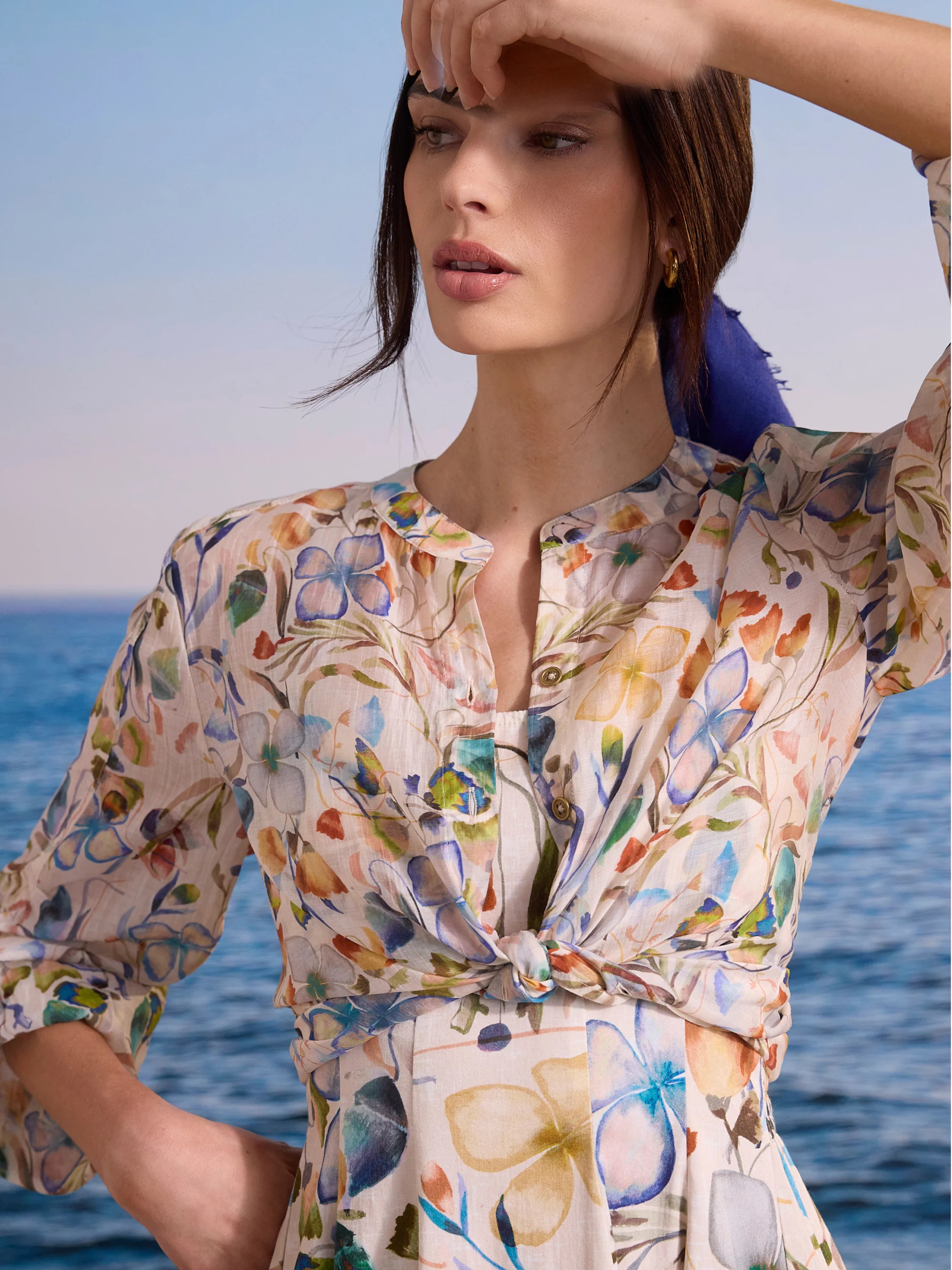 Cream shirt with multi-color watercolor floral pattern. Features a band collar and a tied knot at the front.
