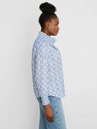 White shirt with blue embroidered tile pattern, a ruffled high collar, and ruffled cuffs.