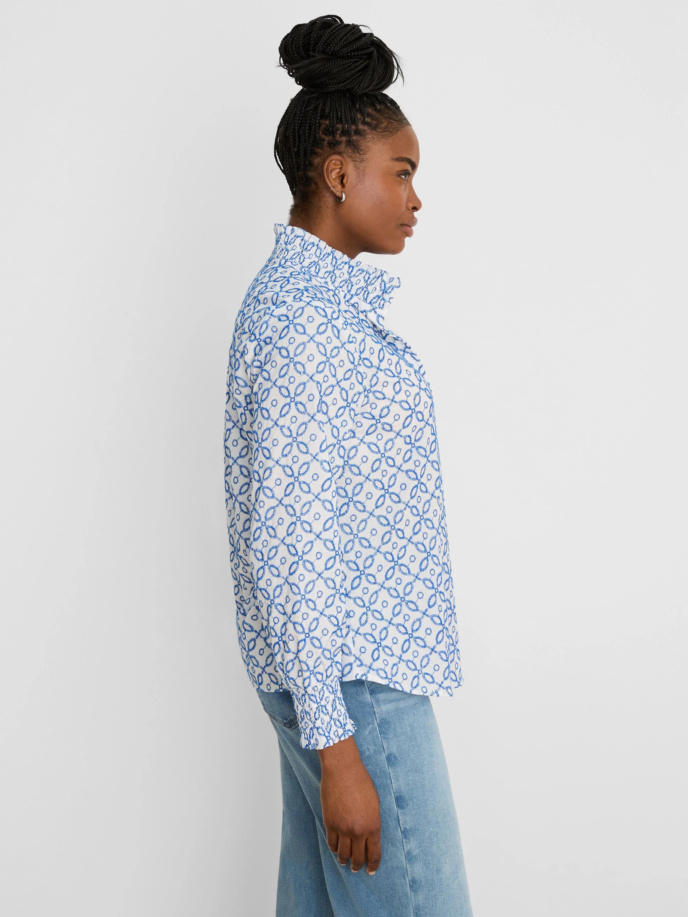 White shirt with blue embroidered tile pattern, a ruffled high collar, and ruffled cuffs.