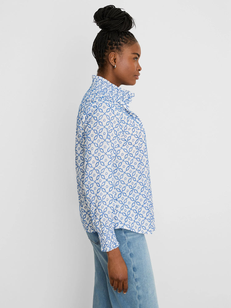 White shirt with blue embroidered tile pattern, a ruffled high collar, and ruffled cuffs.