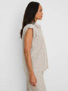 Tan collared sleeveless shirt with shimmering white vertical stripes.