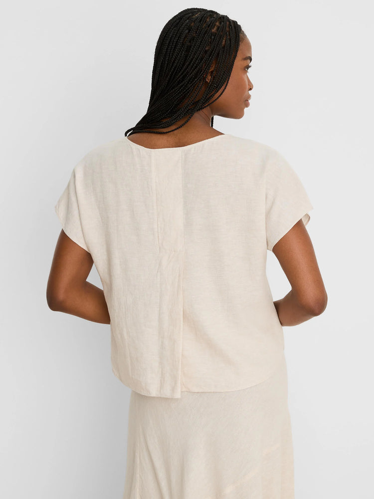 Pale beige linen tee (back view). Loose fit, cap sleeves, shallow scoop neck, with a central vertical seam.