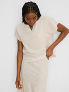 Pale beige linen tee with a split V-neck, short wide sleeves, and visible woven texture.
