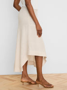 Natural linen midi skirt with a flowing, asymmetrical high-low hem.