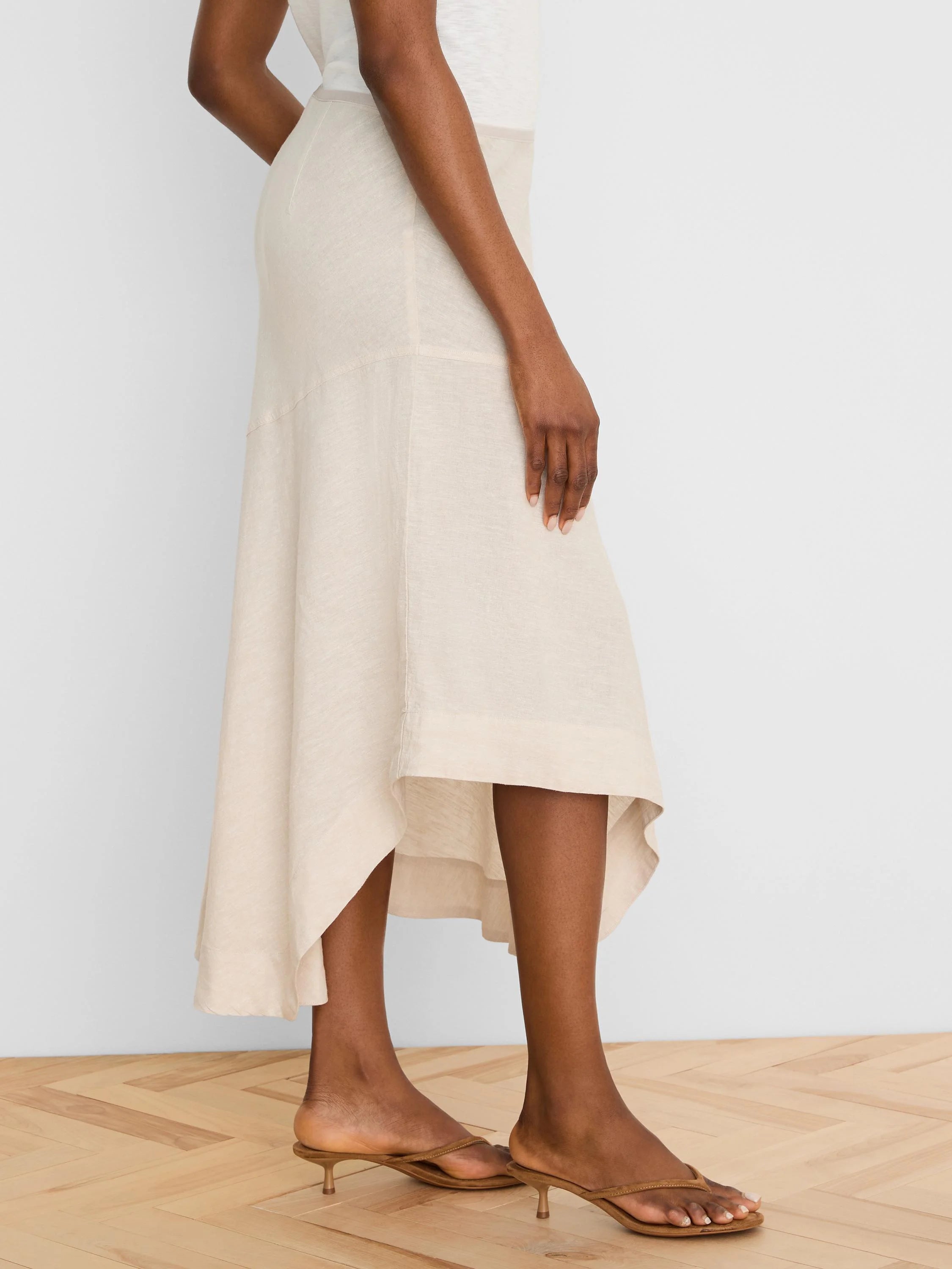 Natural linen midi skirt with a flowing, asymmetrical high-low hem.