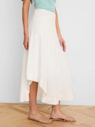 Off-white linen skirt with an asymmetrical, flowing hemline.
