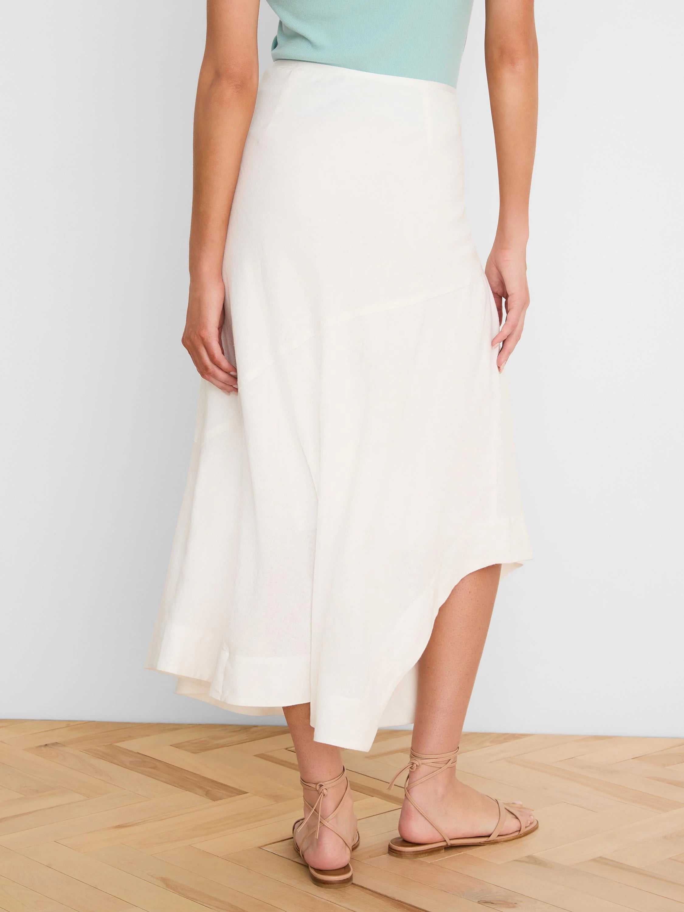 Off-white linen midi skirt with a flowy A-line shape and an asymmetrical hem.
