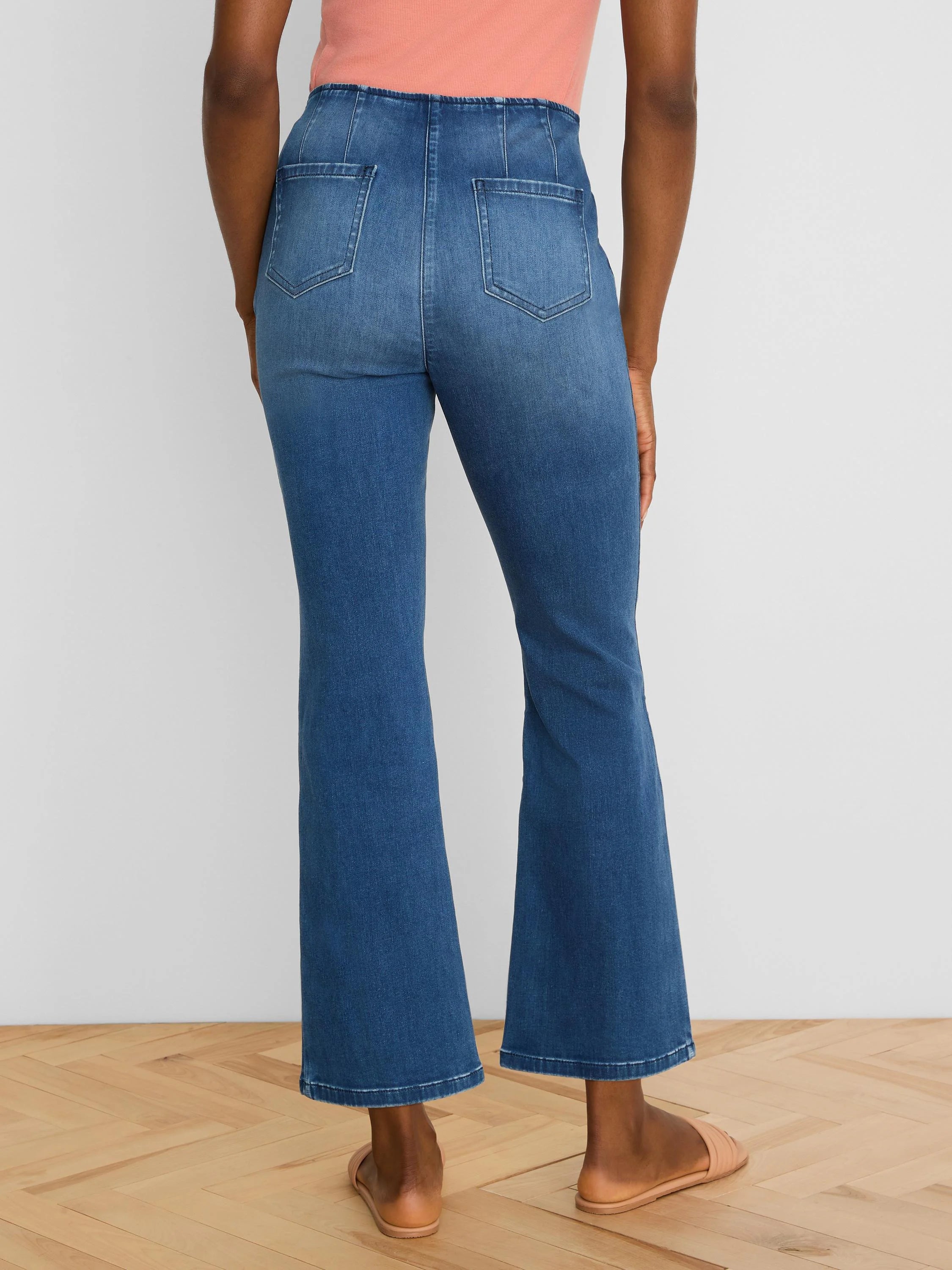 Dark blue, high-waisted bootcut ankle jeans, shown from the back, featuring two back pockets and vertical seams.