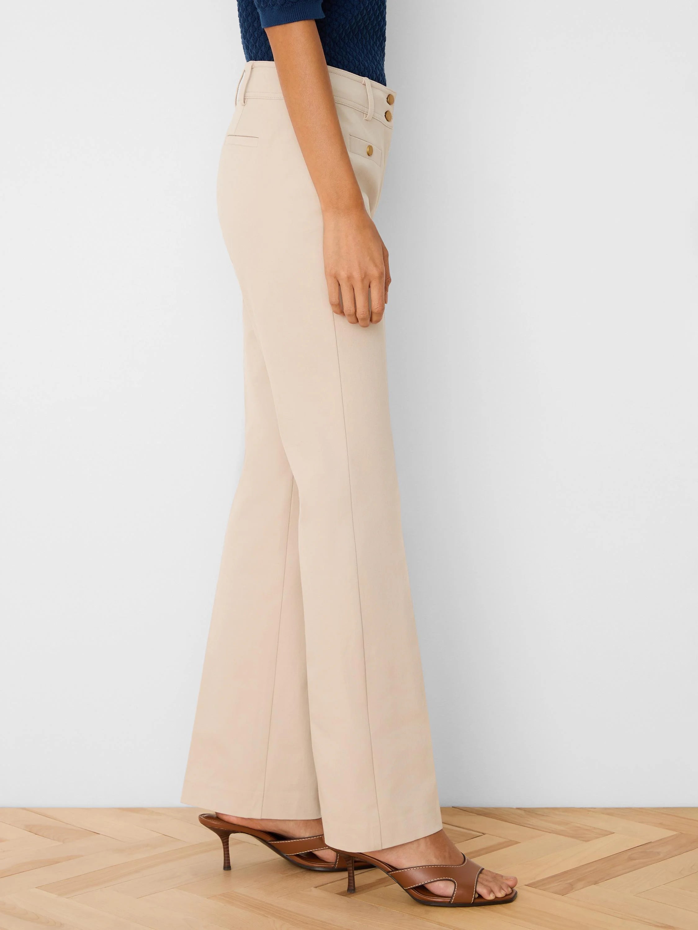 Light beige demi-boot pants with a front crease and gold button details at the high waist.