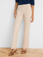 Light beige demi-boot pants with double gold-tone button closure and two front decorative buttoned flap pockets.