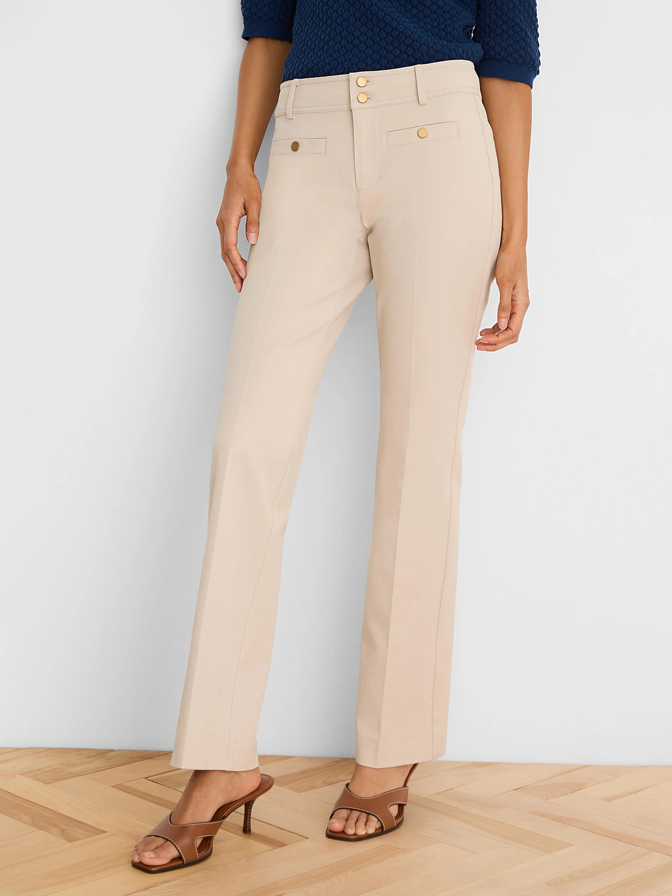 Light beige demi-boot pants with double gold-tone button closure and two front decorative buttoned flap pockets.