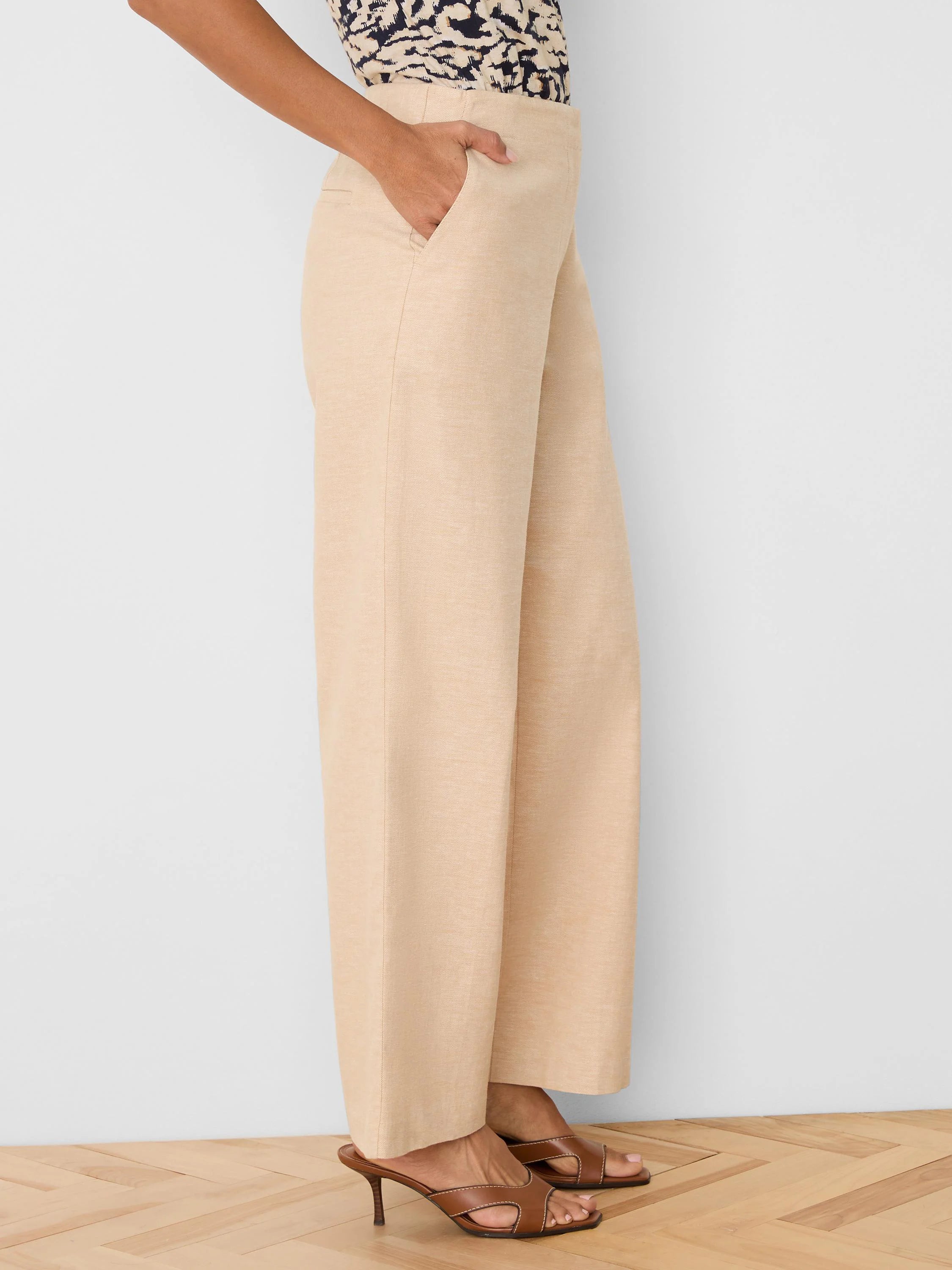 Light beige wide leg linen pants with visible side pockets, shown on a model.