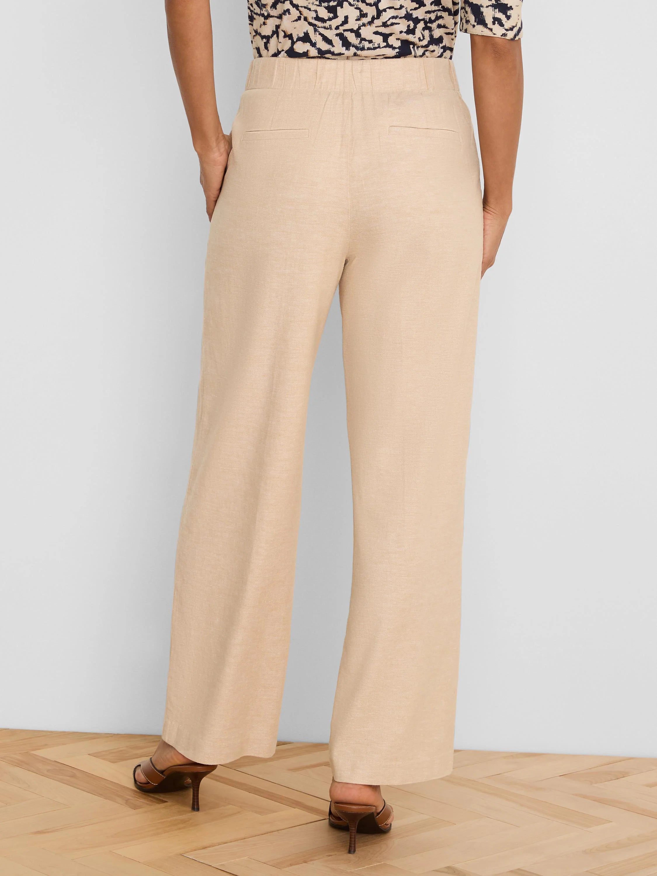Light beige wide-leg linen pants, back view. Features an elastic waist and two rear welt pockets.